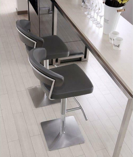 two stainless steel and faux leather barstools in front of a home bar